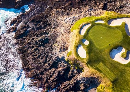 A small planet-like scene with rocky, cratered terrain on the left and a green, glossy creature or mask on the right, partly peeking into view.